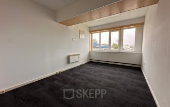 Office space rental available at Zwettestraat 15, Leeuwarden, featuring a clean interior with large windows and black carpet flooring.