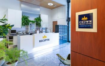 Modern reception area at Pompoenweg 3 - 15 in Leiden, featuring a reception desk, indoor plants, mailboxes, and ample natural light.