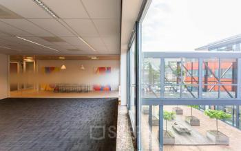 Office space with large windows, colorful artwork on the walls, and adjacent seating area at Pompoenweg 3 - 15, Leiden, ideal for office space rental.