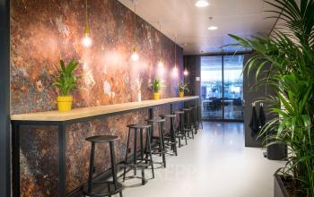 Modern workspace interior at Bargelaan 200, Leiden, with high tables, bar stools, and greenery, available for office space rental.