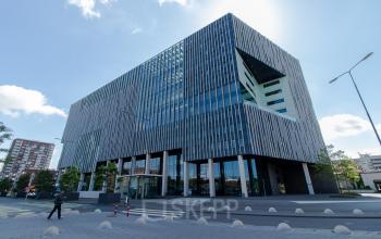 Modern office building at Bargelaan 200, Leiden, offering office space rental with a striking facade and a business professional entering.