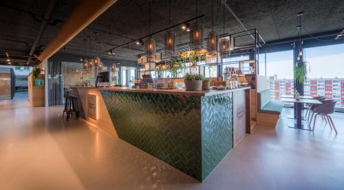 Modern office interior at Bargelaan 200, Leiden, featuring a stylish kitchen area with green tiling, bar stools, and ample natural light.