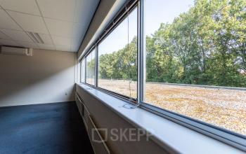 A spacious office to rent located at Fruitweg 38, Leiden, featuring large windows with a view of greenery, ideal for office space rental.