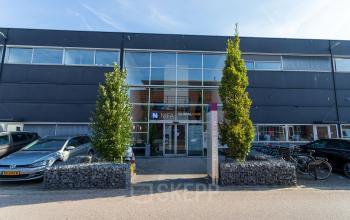 Exterior view of office space rental at Fruitweg 22, Leiden, featuring a modern facade with ample parking and bicycle racks.