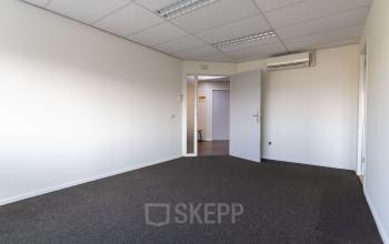 Empty office space at Fruitweg 22, Leiden, ideal for rent. Neutral walls and carpet offer a versatile area for office space rental.