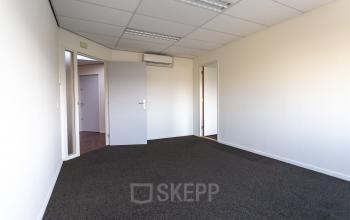 Interior view of unfurnished office space available for rent at Fruitweg 22, Leiden, featuring a carpeted floor and overhead lighting.