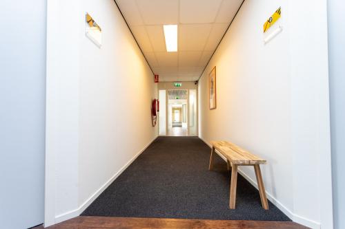 View of a well-lit hallway at Fruitweg 22, Leiden, featuring a wooden bench and bright walls, perfect for office space rental needs.