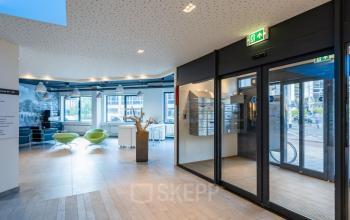Modern office entrance at Schipholweg 55-89, Leiden, featuring spacious reception area with contemporary furniture and lots of natural light, ideal for office space rental.