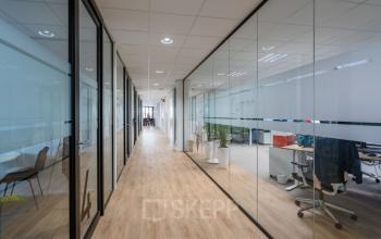 Modern office space at Schipholweg 55-89 in Leiden with glass walls, wooden flooring, and desks in a bright, open layout.