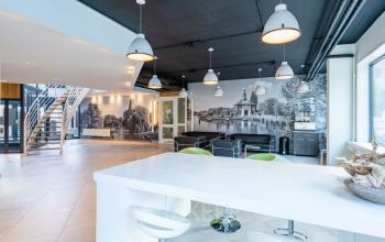 Modern office interior at Schipholweg 55-89, Leiden, featuring a bright workspace with white furniture and seating areas suitable for office space rental.