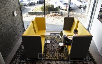 Office space rental at Kanaalpark 140 in Leiden featuring modern seating booths with a person working on a laptop.