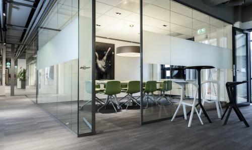 Modern office space to rent at Kanaalpark 140, Leiden, featuring a glass-walled conference room with green chairs and a table.