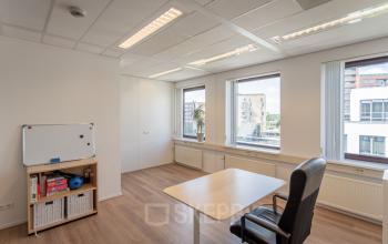 A well-lit office space rental at Kanaalpark 157, Leiden, featuring a desk, storage units, and a whiteboard with city views.