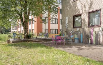 View of a welcoming office space rental at Kanaalpark 157, Leiden with colorful outdoor seating and lush greenery.