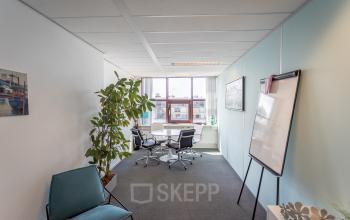 Modern office space rental at Kanaalpark 157, Leiden, with a furnished meeting area and a view outside.