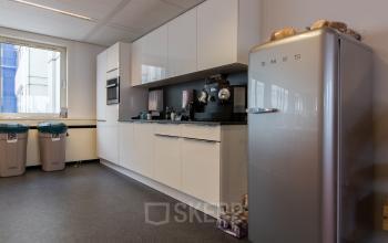 Modern pantry at the office located at Vlietweg 17, Leidschendam with white cabinets, appliances, and a Smeg refrigerator.