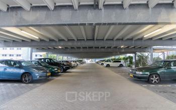 Covered parking area at Vlietweg 17, Leidschendam, with multiple cars parked and office buildings in the background.