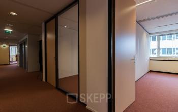 Empty office spaces with open wooden doors and glass partitions in an office building at Vlietweg 17, Leidschendam.