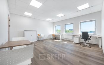 Bright office space rental at Het Ravelijn 1-11, Lelystad, featuring modern furnishings with desks, chairs, and natural light from large windows.