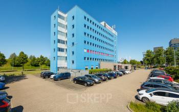 Exterior view of Het Ravelijn 1-11, Lelystad, showcasing a vibrant blue office building with ample parking space, ideal for office space rental.
