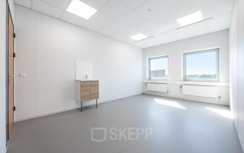 Bright, unfurnished office space with large windows at Het Ravelijn 1-11, Lelystad, ideal for rent office space setups, featuring natural light and a modern sink unit under a white ceiling.