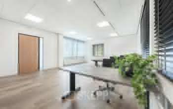 Bright, modern office space at Het Ravelijn 1-11, Lelystad featuring large windows, sleek wooden flooring, and essential furnishings ideal for an efficient work environment. Perfect for office space rental.