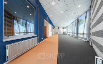 Spacious office interior at Het Ravelijn 1-11, Lelystad, with large windows allowing abundant natural light; ideal for open floorplan workspaces. Perfect for those seeking office space rental in a modern setting.