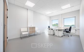 Bright office space at Het Ravelijn 1-11, Lelystad, featuring two chairs, a desk, and large windows offering natural light. Ideal for workspaces seeking an inviting atmosphere for productivity. Office space rental available.