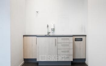 Small minimalist pantry with light wood cabinets and a polished countertop inside Het Ravelijn 1-11 office, Lelystad, ideal for office space rental seekers.
