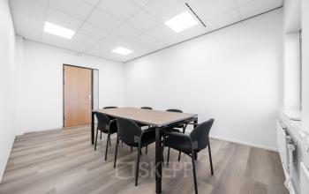 Bright conference room with wooden table and six black chairs at Het Ravelijn 1-11, Lelystad, ideal for office space rental.