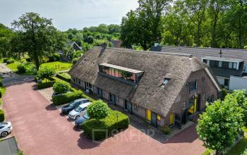 Exterior view of office space at Hamersveldseweg 120, Leusden, featuring a rustic building with a thatched roof and ample parking.