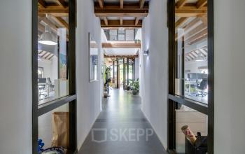 Bright office space with wooden beams, plants, and modern furnishings on Hamersveldseweg 120, ideal for businesses seeking office space rental in Leusden.