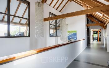 Bright office corridor with wooden beams and chandeliers at Hamersveldseweg 120, Leusden, available for office space rental.