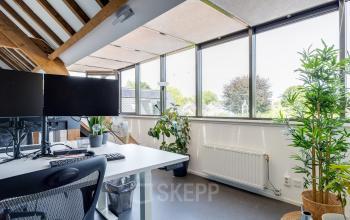 Bright, furnished office space with large windows, plants, and workstations available for rent at Hamersveldseweg 120, Leusden.