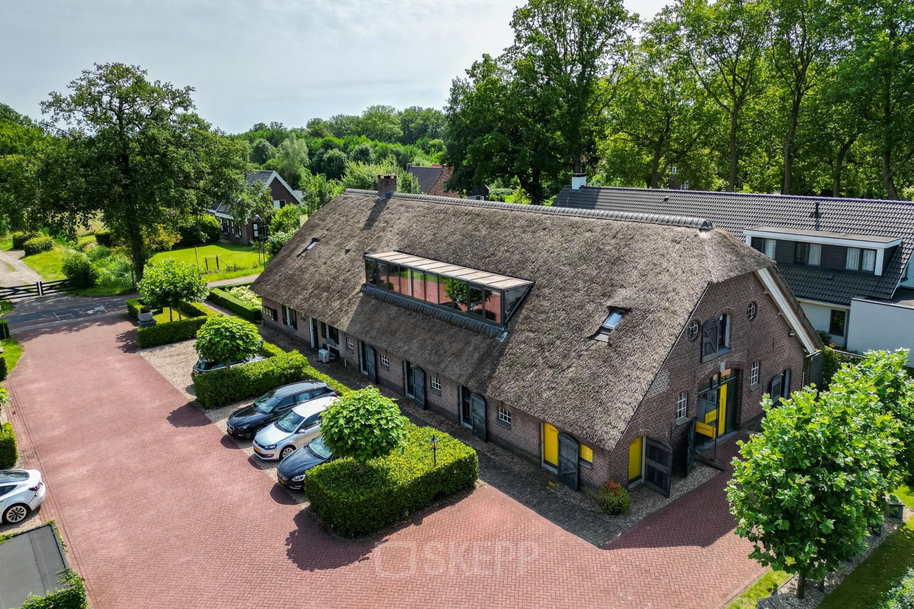 Exterior view of office space at Hamersveldseweg 120, Leusden, featuring a rustic building with a thatched roof and ample parking.