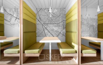 Modern gestaltete Arbeitsnischen mit grünen Sitzpolstern und städtischen Wandbildern in einem Büro zur Miete am Promenade 23, Linz.