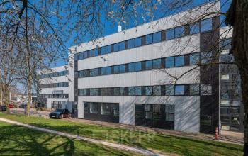 Modern office building exterior at Horsterweg 24, Maastricht-Airport, surrounded by trees and a grassy area, ideal for office space rental.