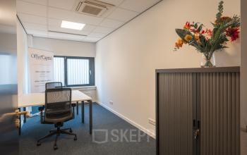 Bright office space at Horsterweg 24, Maastricht-Airport, featuring a modern desk, ergonomic chair, and vibrant flowers on a cabinet, ideal for office space rental.