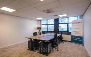 Office space for rent at Horsterweg 24 in Maastricht-Airport, featuring a well-lit interior with a large conference table, chairs, and window view for business activities.