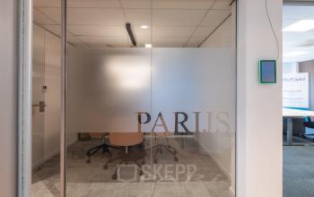 Interior view of a minimalist conference room at Horsterweg 24, Maastricht-Airport, featuring frosted glass walls and modern office chairs, ideal for office space rental.