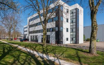 Exterior view of a modern office building at Horsterweg 24, Maastricht-Airport, ideal for office space rental, surrounded by trees and grass.
