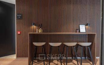 Office interior at Horsterweg 24, Maastricht-Airport with a sleek wooden wall and bar-height seating for collaboration. Ideal for office space rental.