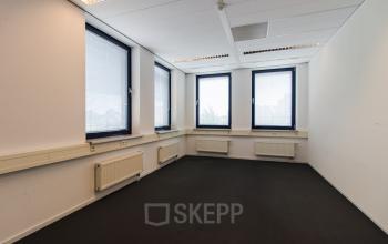 Empty office space with large windows located at Europalaan 24 in Maastricht-Airport, available for rent.