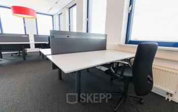 Modern office space rental at Europalaan 24, Maastricht-Airport, featuring workstations with chairs, large windows, and ample lighting.