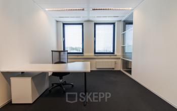 Well-lit office space rental at Europalaan 24, Maastricht-Airport with a modern desk, chair, and shelving unit.