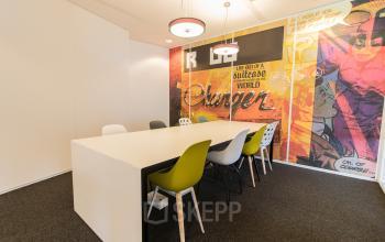 Bright conference room at Europalaan 24, Maastricht-Airport with a large table and colorful chairs, suitable for office space rental.