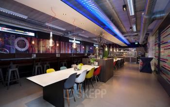 Interior of office space at Europalaan 24, Maastricht-Airport, featuring a modern communal table and vibrant seating in a well-lit area.