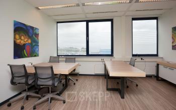 Office space at Europalaan 24, Maastricht-Airport with large windows, desks, office chairs, and colorful wall art.