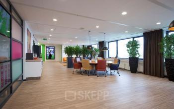 Modern office space at Europalaan 24, Maastricht-Airport with collaborative work areas, large windows, plants, and colorful seating.
