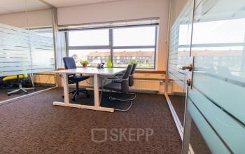 Bright office space with glass walls at Avenue Ceramique 221, Maastricht, featuring a desk and chairs ideal for office space rental.